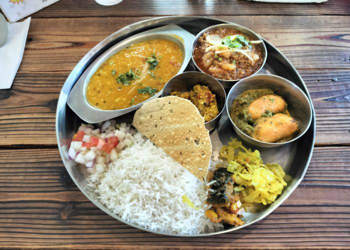A vegan curry set at Ganesh N, featuring two curries, rice and side dishes.
